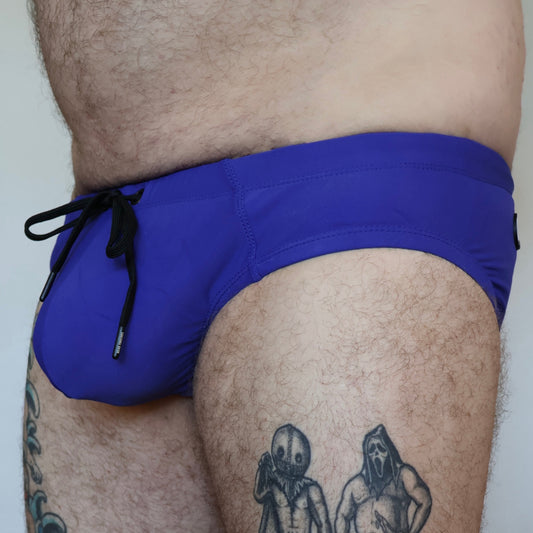 Person wearing blue swim shorts with tattoos visible on the legs.