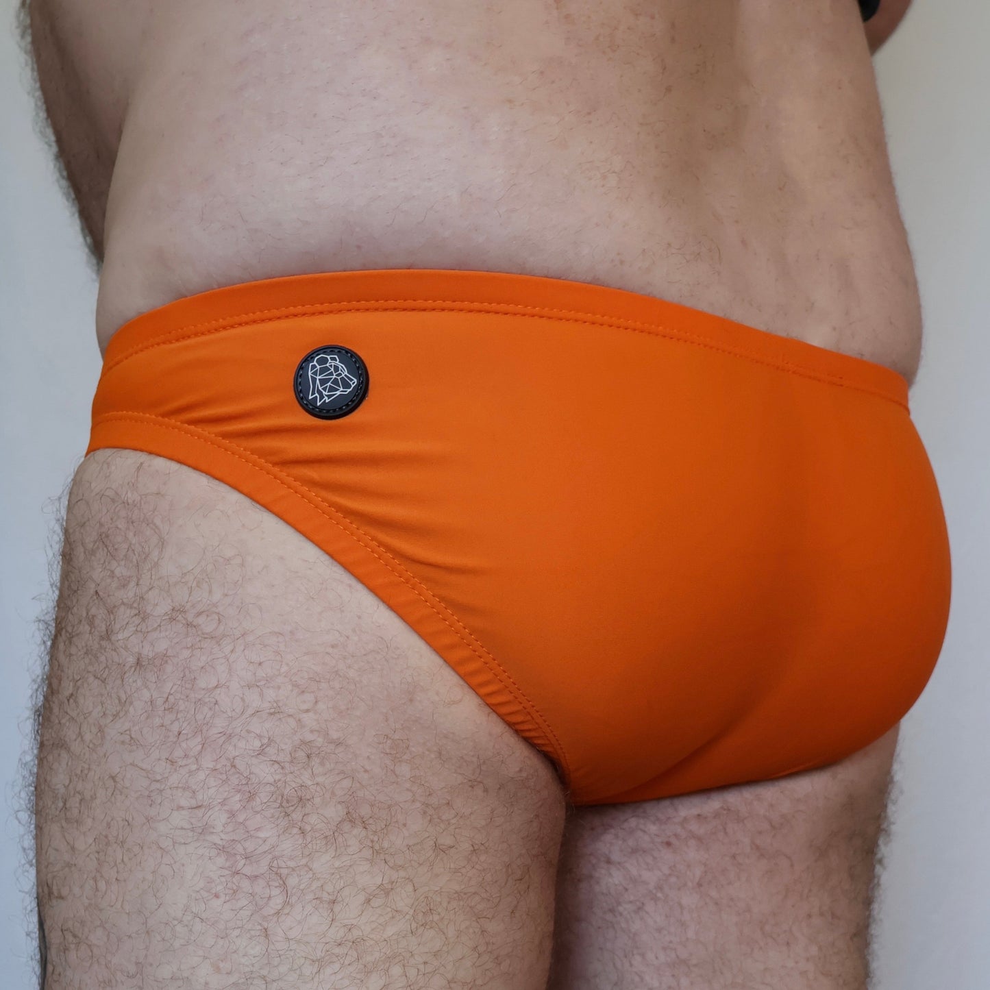 Orange swim brief with a brand logo on a plain background